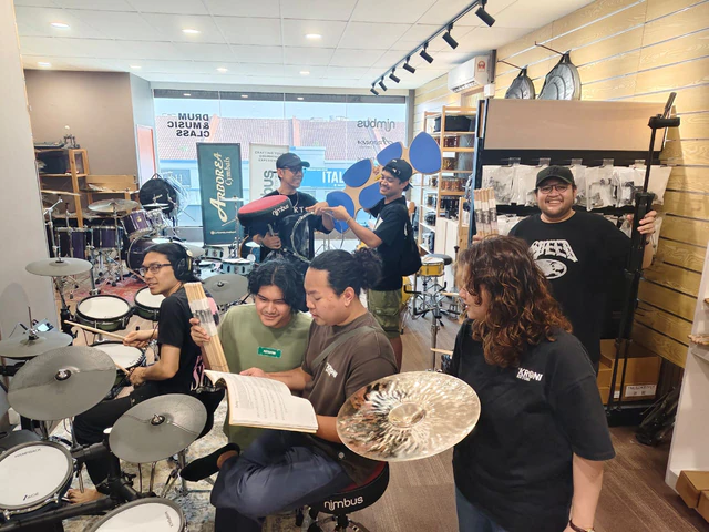 A group of customers with drums, cymbals, sticks and hardware at Soma Music