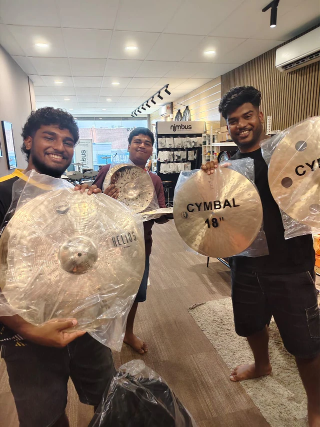 Three customers holding cymbals inside Soma Music