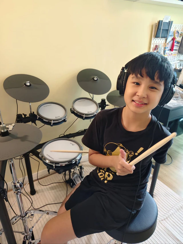 Young drummer holding drumsticks at a home electronic drum setup in Malaysia
