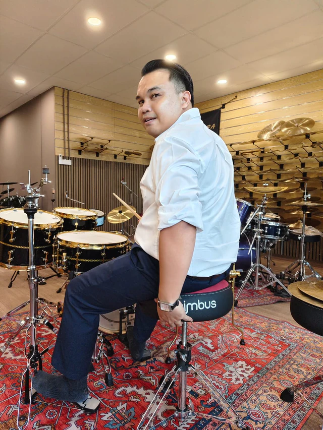 Customer seated on a Nimbus drum throne beside acoustic drum kits