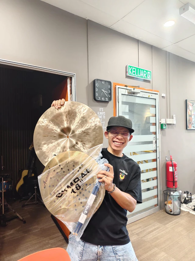 Customer holding cymbals at the Soma Music showroom