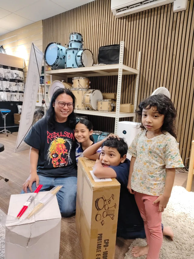 A family collecting a portable digital drum kit from Soma Music in Ampang