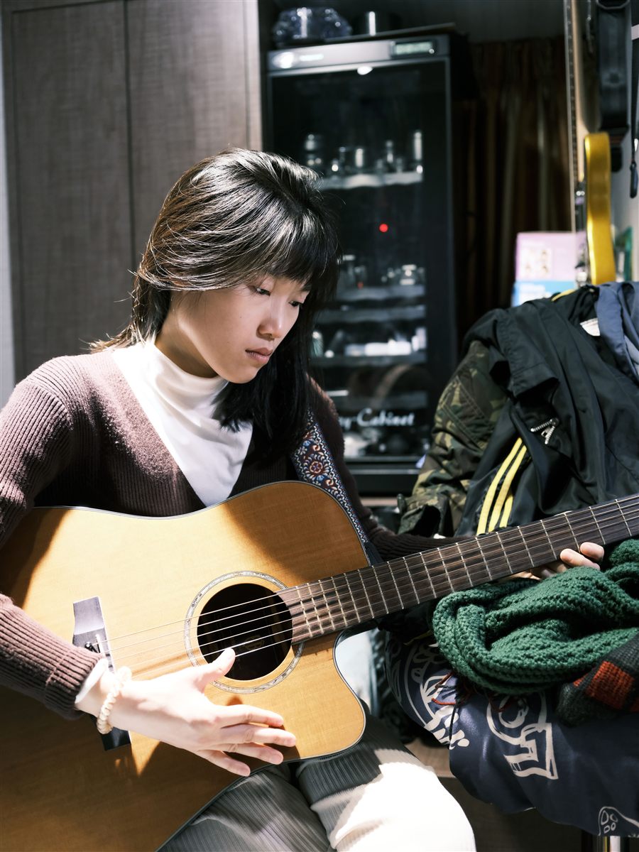Asian adult practising acoustic guitar at home