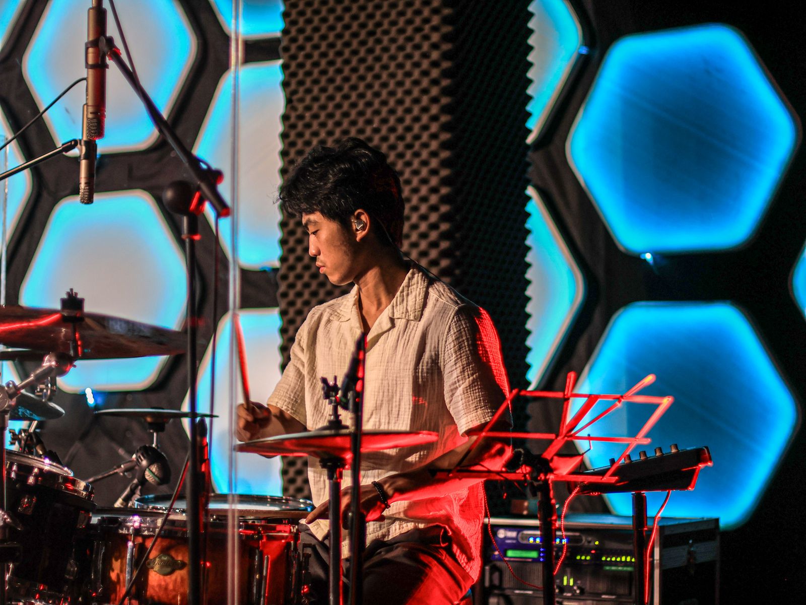 Asian drummer performing on stage under concert lighting